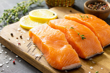 Fresh Fish. Raw Salmon Fillet, Lemon and Spices on a rustic wooden board on a stone table.