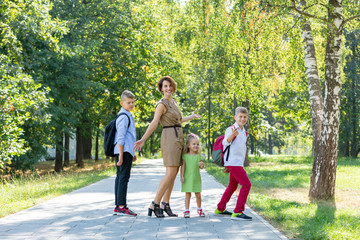 Obraz premium Happy young family, mother with three children walking in the park. Healthy lifestyle concept