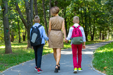 Obraz premium Happy young family, mother with two boys walking in the park. Healthy lifestyle concept