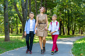 Happy young family, mother with two boys walking in the park. Healthy lifestyle concept