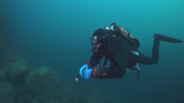 Scuba diver swimming deep in underwater wild nature of Lake Baikal.