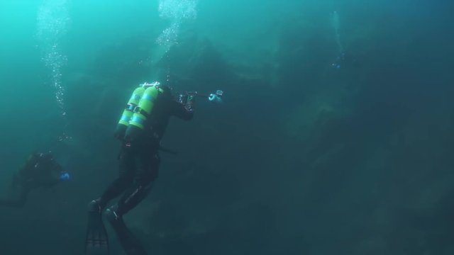 Scuba diver cameramen with group swimming deep underwater in Lake Baikal.