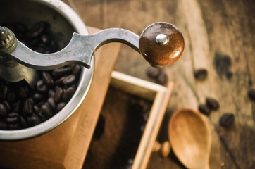 Old vintage coffee grinder with grains of coffee on a wooden table. retro style.  Copy-space. selective focus.