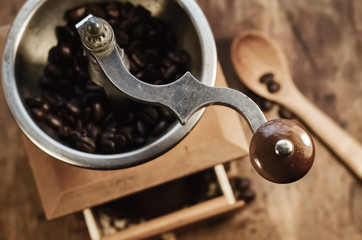 Old vintage coffee grinder with grains of coffee on a wooden table. retro style.  Copy-space. selective focus.