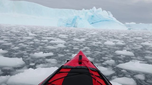 kayaking in Antarctica, red canoe boat  moving through the ice