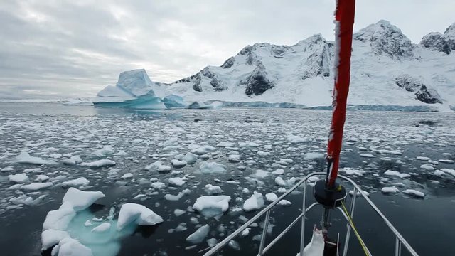 sailing boat travel in Antarctica, yacht navigation through icebergs and sea ice
