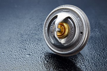Obraz premium Thermostat engine cooling system of the internal combustion machine. Spare parts on a dark background