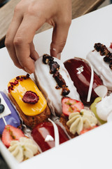 Male hand taking delicious eclair with glaze, colorful dessert