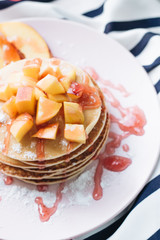 Stack of delicious homemade pancakes with sauce and sliced apple