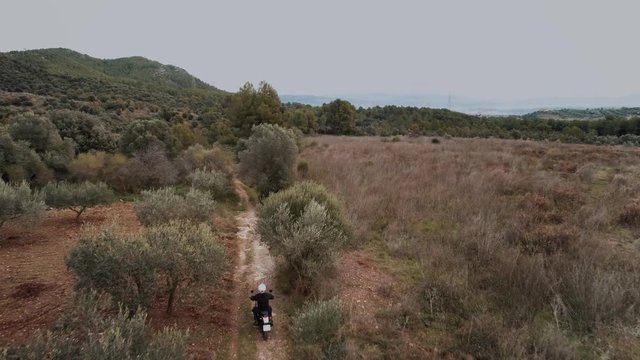 Drone aerial shot of two friends on offroad enduro motorcycles drive on empty farm backcountry road. Small trail winds in trees and farms, technical and extreme handling skills on motorcycles