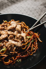 Delicious spicy noodles with meat in black plate, traditional Aisan food