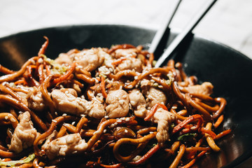 Delicious spicy noodles with meat in black plate, traditional Aisan food