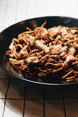 Delicious spicy noodles with meat in black plate, traditional Aisan food