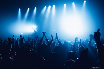 silhouettes of concert crowd in front of bright stage lights. Unrecognized people in crowd. Copy...