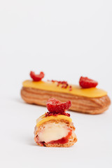 Set of delicious eclairs with yellow glaze and raspberries