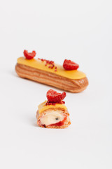 Set of delicious eclairs with yellow glaze and raspberries