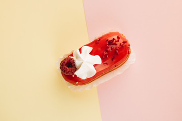 Delicious eclair with red glaze and raspberry, sweet dessert