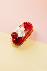 Delicious eclair with red glaze and raspberry, sweet dessert
