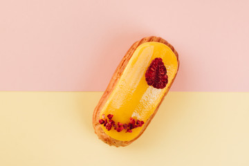 Delicious eclair with red glaze and raspberry, sweet dessert