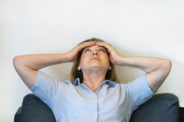 Elderly woman suffering from headache migraine pain at home. Health problem, stress and depression. Female holds head with hand. Concept of health.