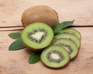 Kiwi fruit whole and sliced on a wooden table.