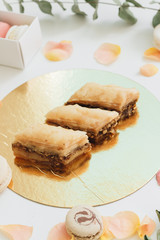 Baklava sweet dessert and pink roses. Pastry made of layers of filo filled with chopped nuts and sweetened and held together with syrup or honey