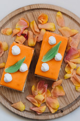 Two pieces of delicious cake on wooden board decorated with floral petals