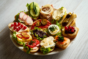 plate with colorful and healthy sandwiches or tapas on a light wooden table