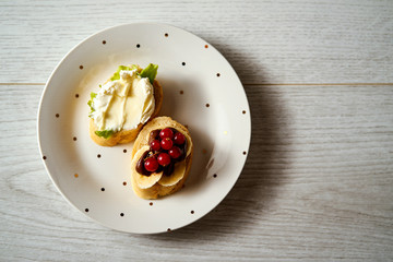 plate with a vegetarian mini-sandwich set with brie cheese, currant lettuce, chocolate and banana on a wooden table