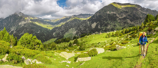 Happy woman hiker travels in Pyrenees Mountains in Andorra and Spain. Nordic walking, recreation and trekking along GR11 path trail - obrazy, fototapety, plakaty