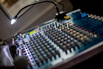 Plakat Selective focus or shallow depth of field night photo of audio mixer with small lamp switched on and microphone. Blurred background