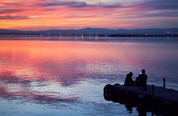 Family taking pictures in the sunset of the calm waters of the Albufera de Valencia, Spain.