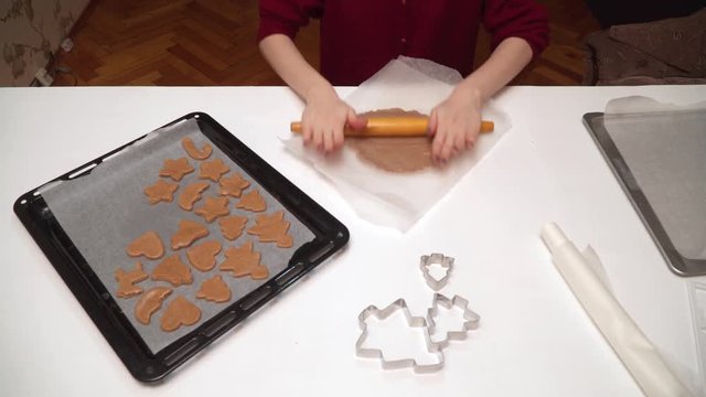 Close up of girls hands making homemade gingerbread cookies. Christmas baking. Dough and form for ginger cookies. Girl rolls dough and cut figures with cookie cutter