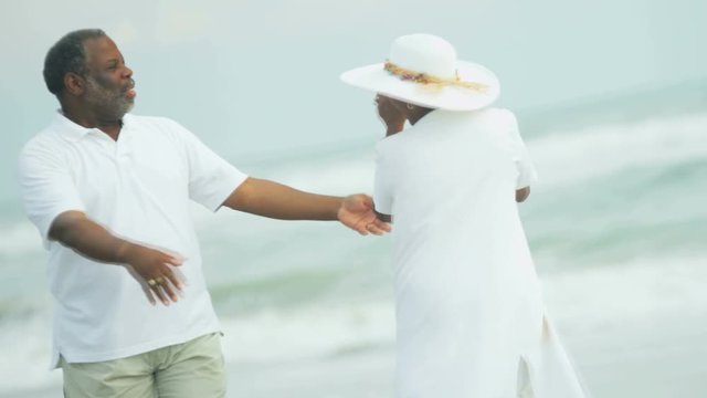 Ethnic male and female wearing white beach clothes having fun dancing in 