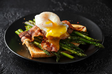 Benedict poached Duck egg with crispy bacon and fried asparagus on toasts for breakfast