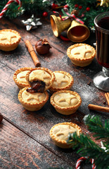 British Christmas mince pies with decoration, gifts, green tree branch on wooden rustic table