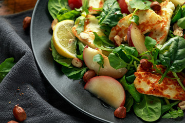 Grilled Halloumi Cheese salad with peach fruit, nuts and spinach, arugula mix. healthy food. closeup