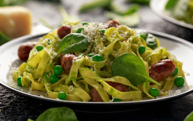 Homemade Pasta with green peas, spinach pesto and sausages. parmesan cheese. healthy food. close up