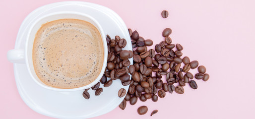 grains of roasted coffee scattered from a cup on a pink background, copy space. Top view