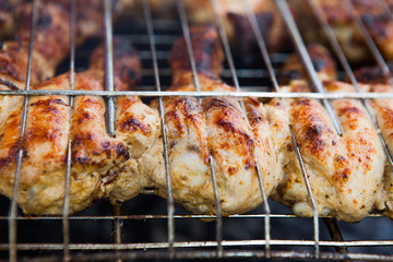 Marinated chicken legs on the grill in the smoke. A picnic, tasty food. BBQ