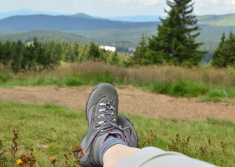 Legs in tracking shoes resting on a mountain field