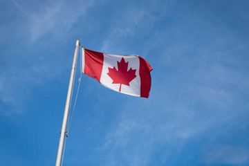 Waving Canadian flag against the blue sky.