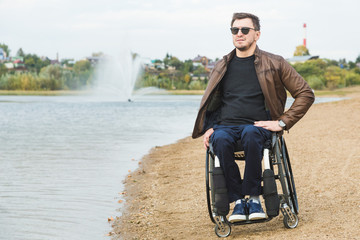 Young man sitting in a wheelchair by the lake.