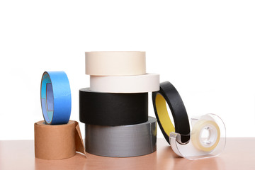 Different types of tape on a wood table and white background