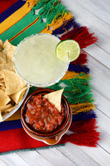 Margaritas and Mexican food on a colorful  table cloth and wood table with chips and salsa