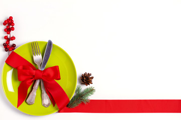Christmas composition with plate, cutlery, pine branches, ribbon and red berries on white table....