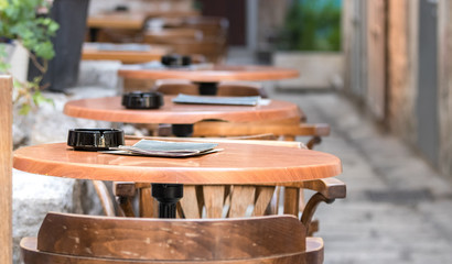 Perspective of wooden tables with an ashtray outside a bar in Split, Croatia.