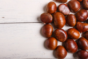pile of sweet chestnuts on white wooden background