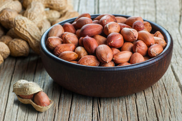 Peanut in nutshell on wooden backrop in bowl. Composition of peanuts serving to make oil, peanut...