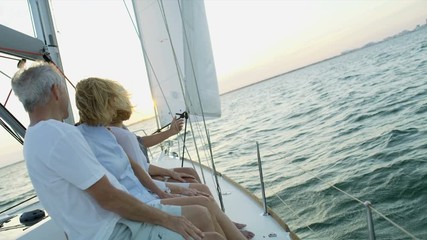 Mature American male and female friends outdoors on their sailing boat at sunrise enjoying their vacation and retirement living  